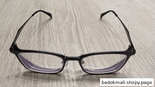 Black-framed eyeglasses resting on a light wooden surface.