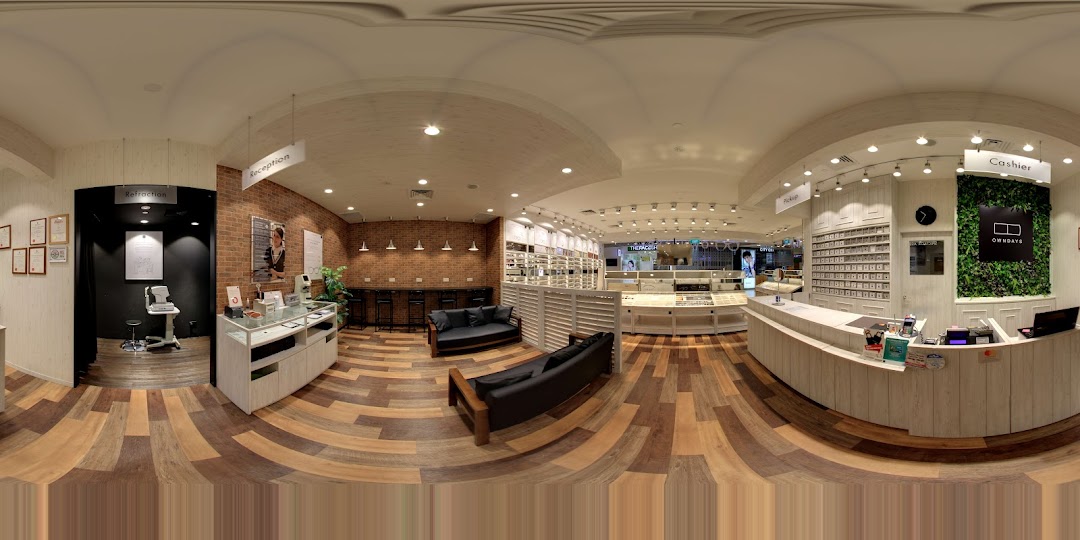 Interior view of a modern optical shop with displays, reception, and seating areas.
