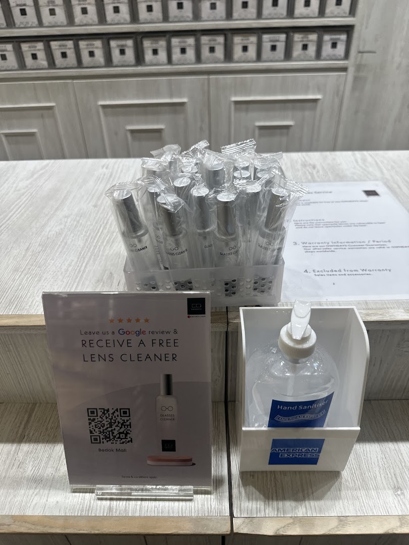 A display of lens cleaners, a review sign, and hand sanitizer on a counter.