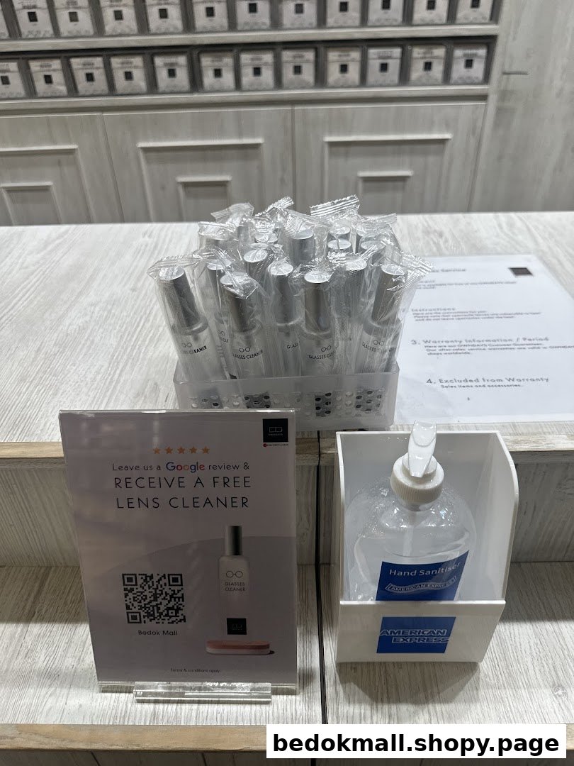 A display of lens cleaners, a review sign, and hand sanitizer on a counter.