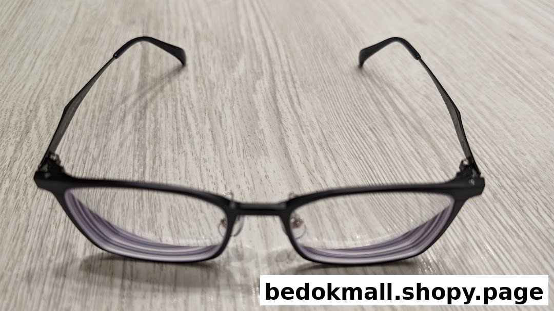 Black-framed eyeglasses with clear lenses resting on a light wooden surface.