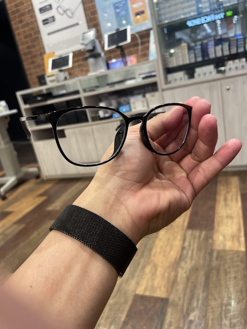 A hand holds eyeglasses inside an optical shop.