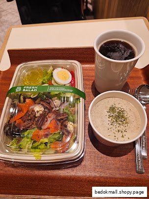 A meal on a tray with a fresh salad, soup, and a cup of coffee.