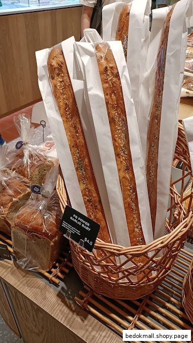 Baguettes in paper sleeves displayed in a wicker basket with a price tag.