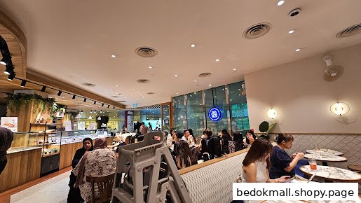 Interior of a busy cafe with customers, tables, and food display cases.