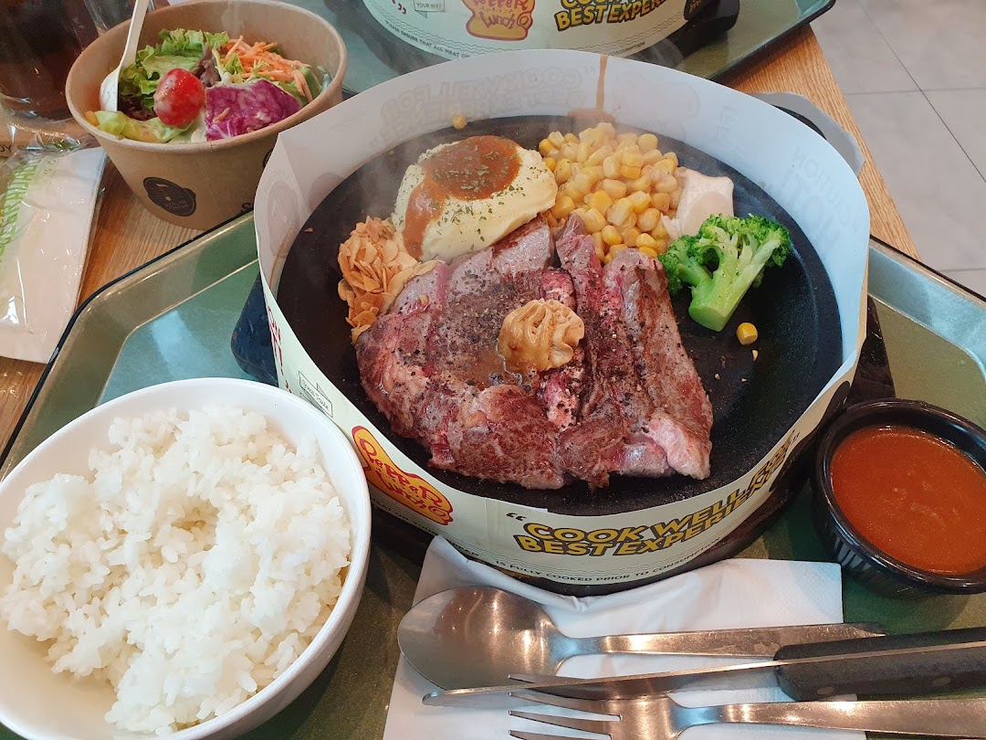 A close-up of a steak meal with rice, salad, and sauce on a table.