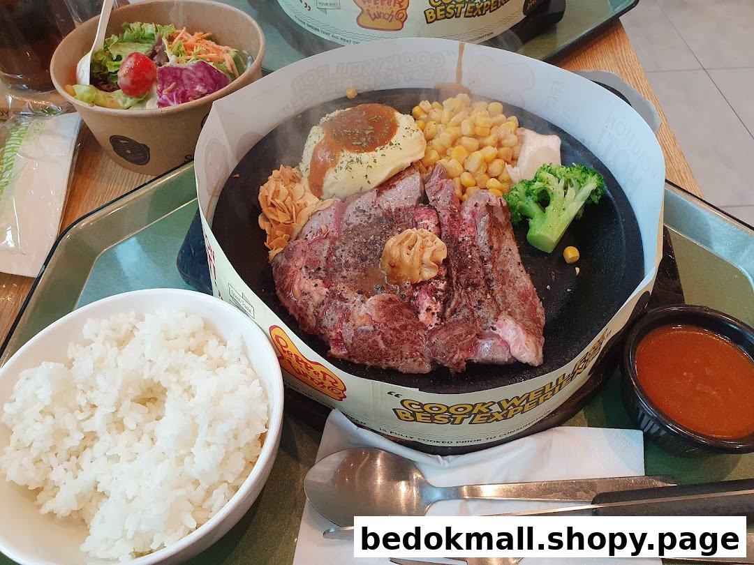 A close-up of a steak meal with rice, salad, and sauce on a table.