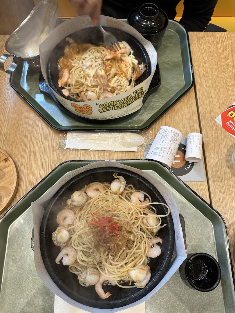 Two hot plates of steaming spaghetti and seafood served at a restaurant.