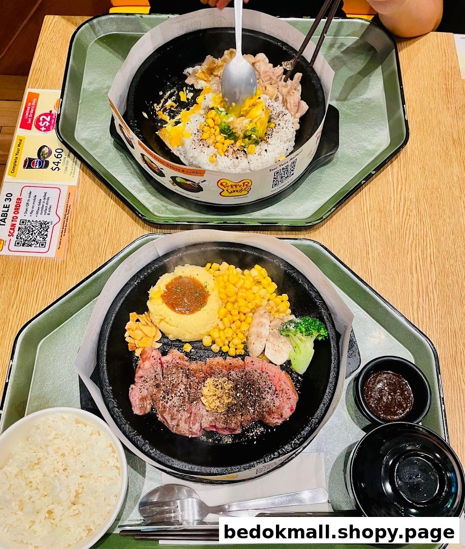 Two hot plates of food, including steak and rice dishes, on a table.