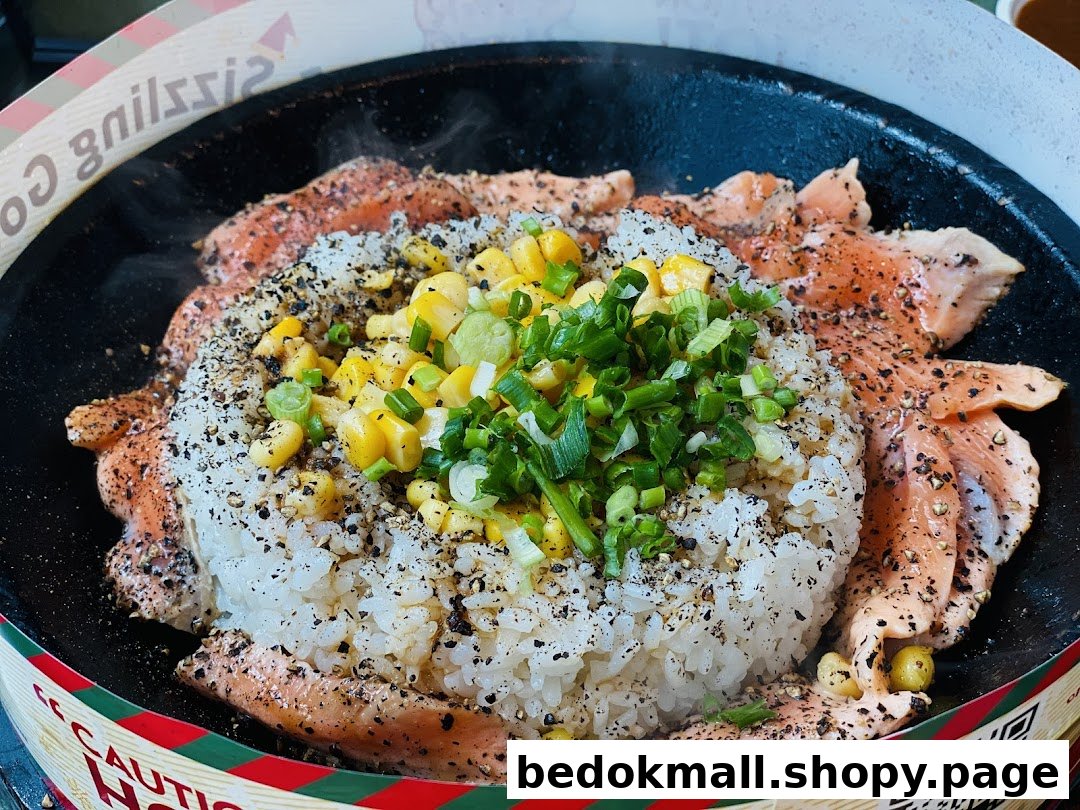 Sizzling salmon and rice dish with corn and green onions on a hot plate.