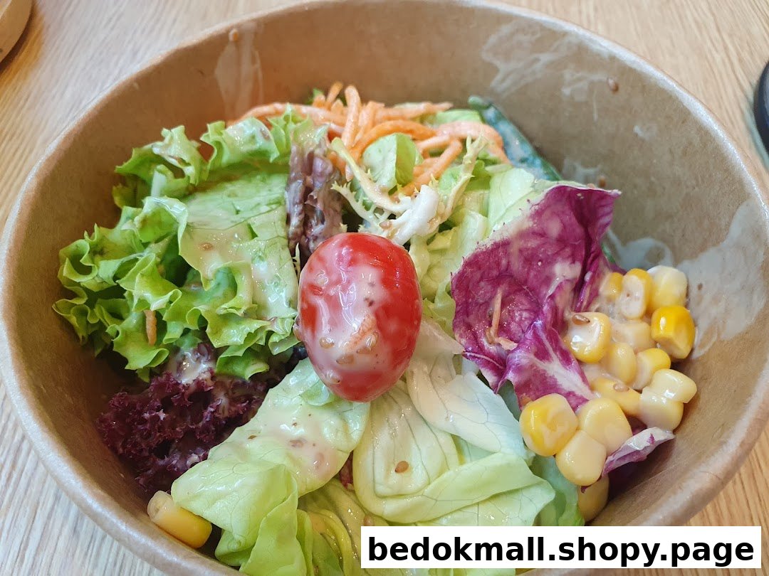 A close-up of a fresh salad with greens, tomato, and corn in a bowl.