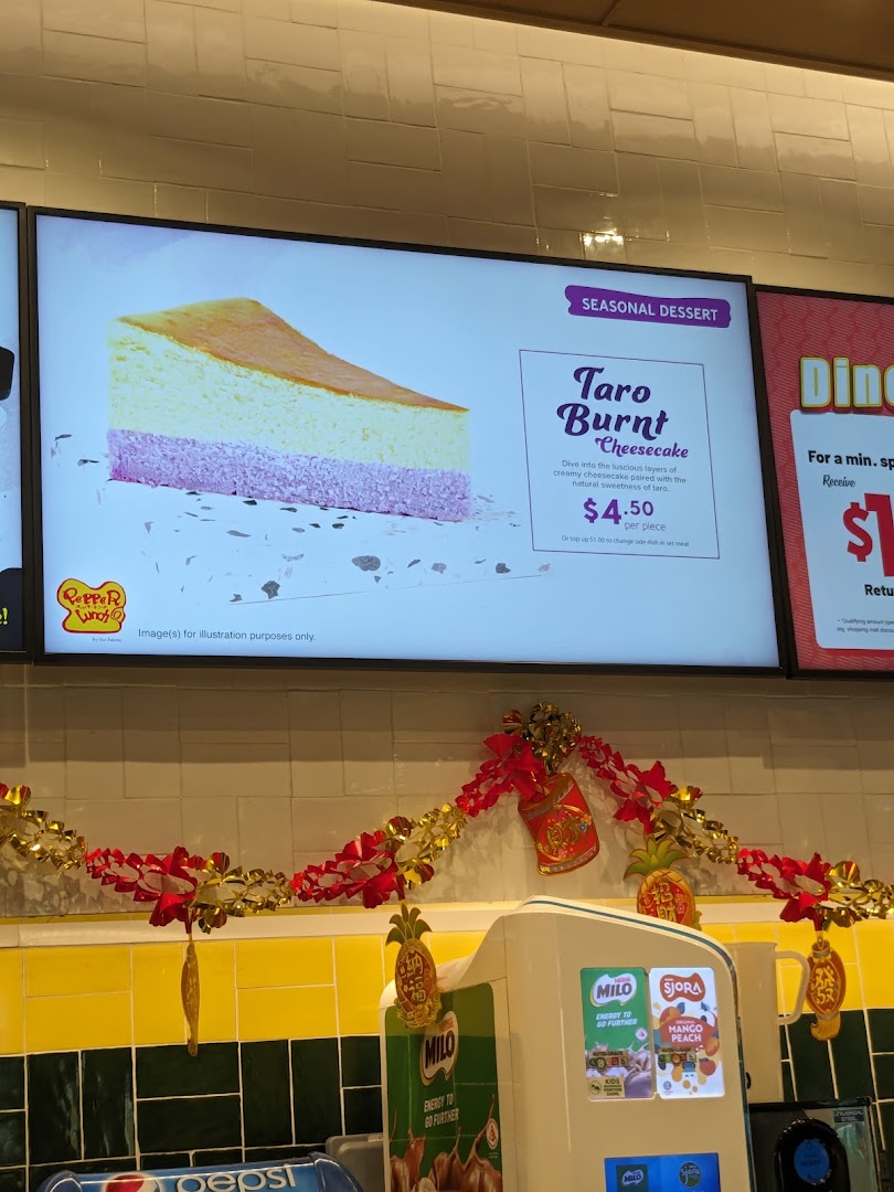 Digital menu board displaying cheesecake and price above a decorated counter.