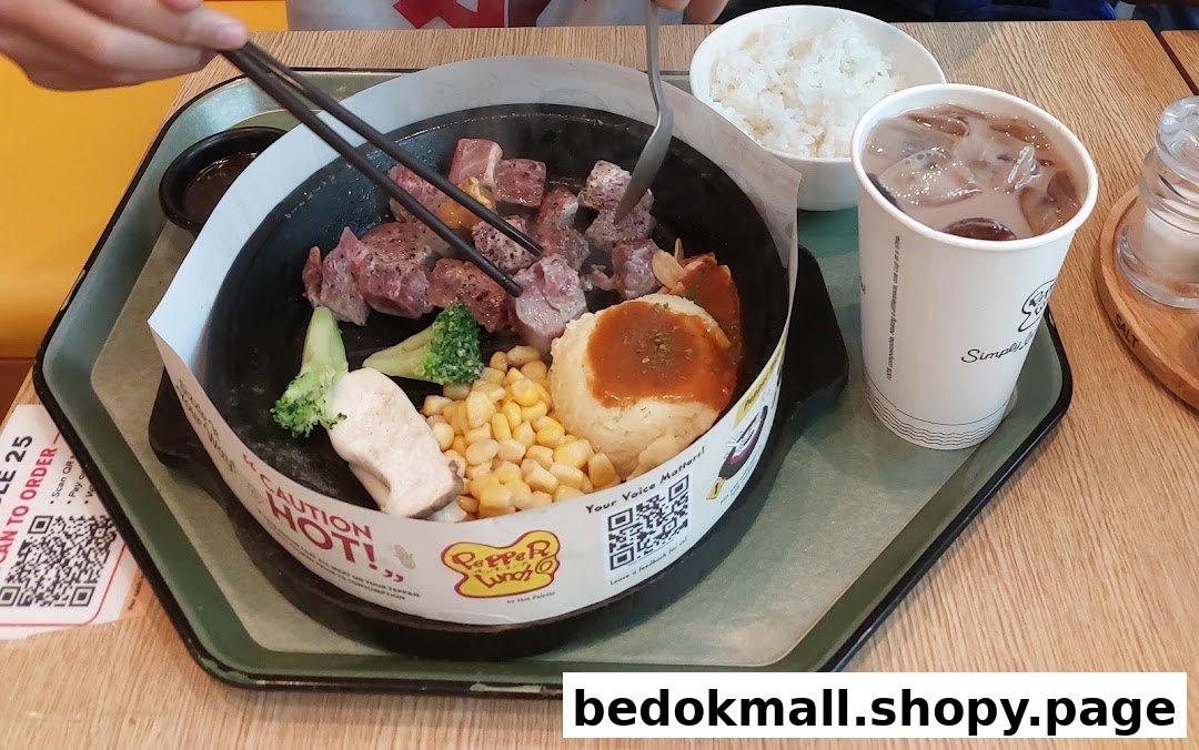 Person eating a hot plate meal with steak, vegetables, rice, and a drink.