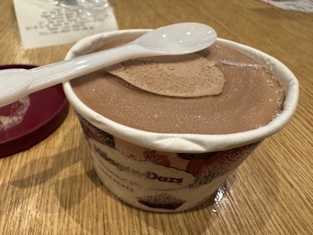 Chocolate ice cream cup with spoon on a wooden table.