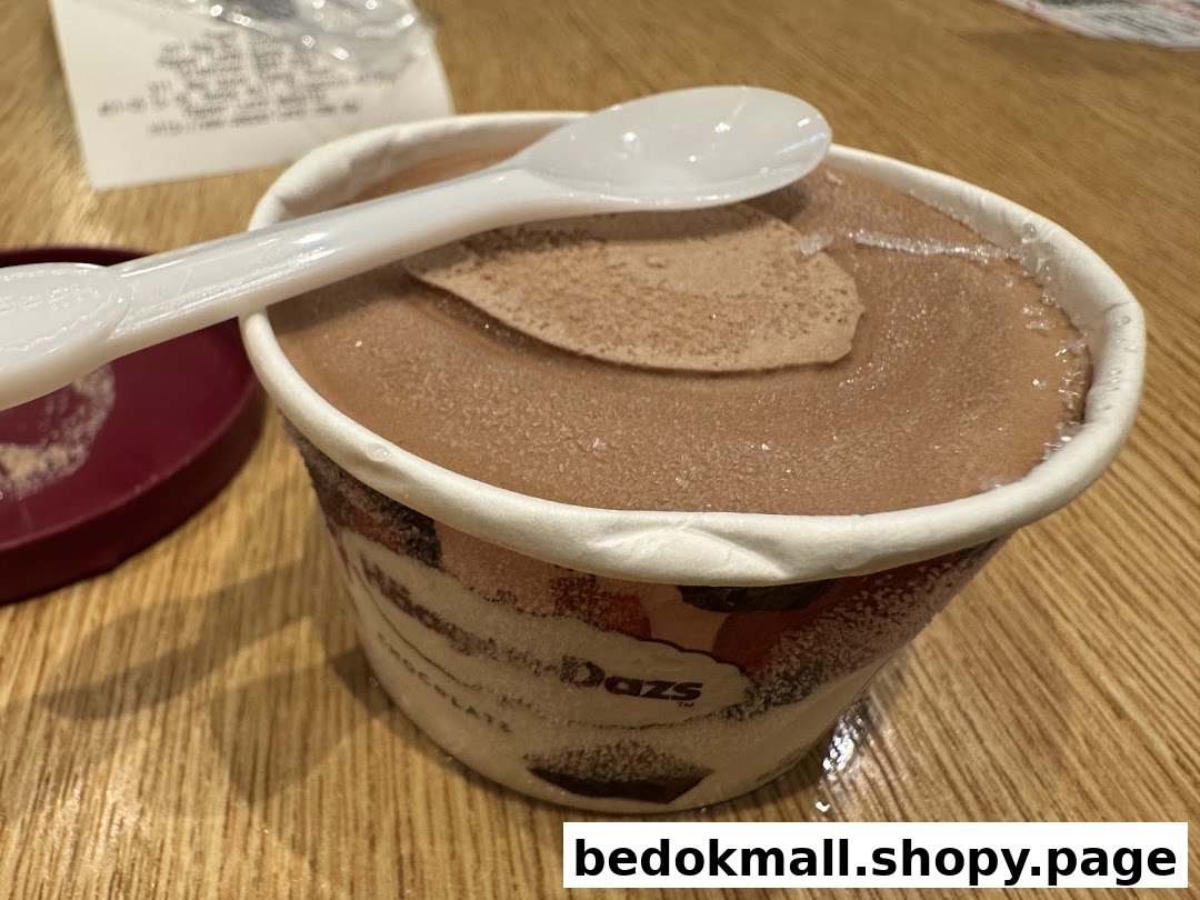 Chocolate ice cream cup with spoon on a wooden table.