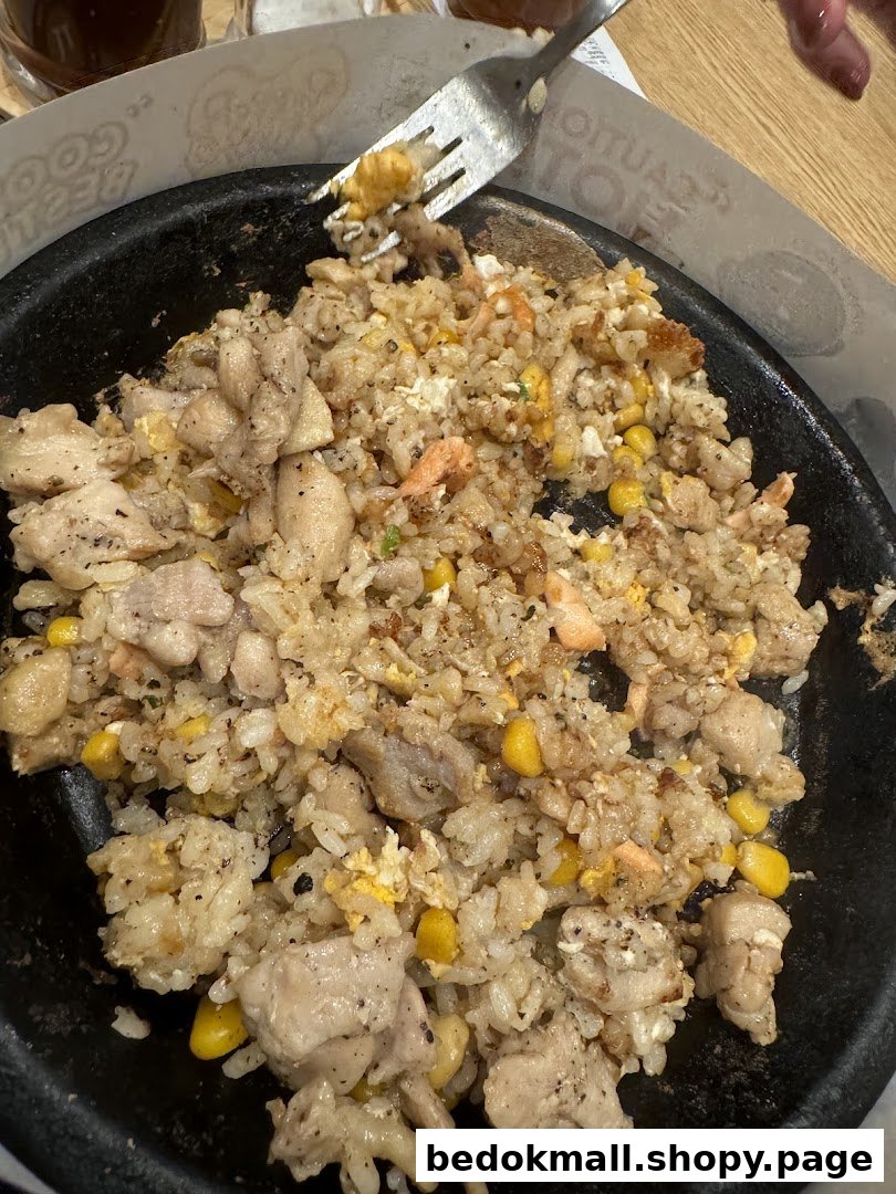 A hot plate of fried rice with chicken, corn, and salmon.