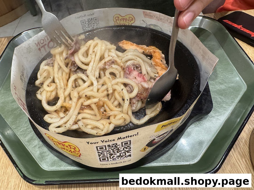 Person stirring noodles and meat on a hot plate at Pepper Lunch.