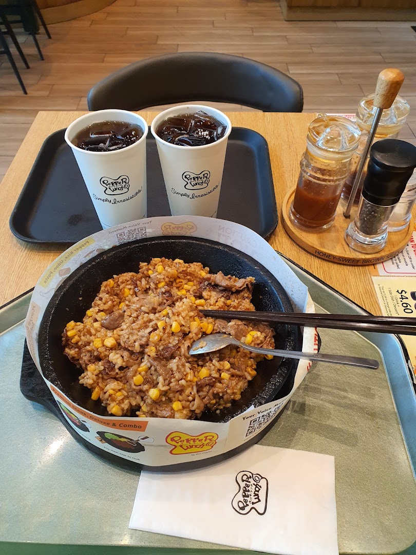 A hot plate meal with rice, meat, corn, and two drinks on a table.