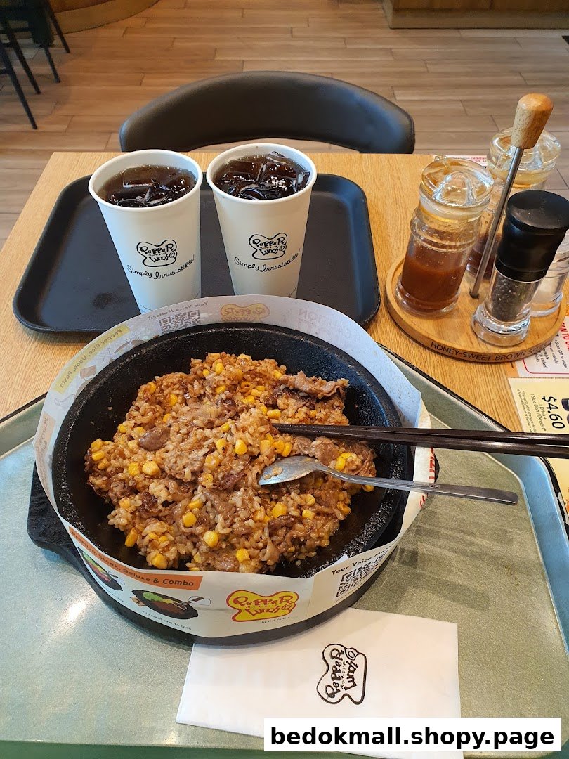 A hot plate meal with rice, meat, corn, and two drinks on a table.