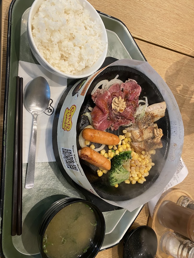 A hot plate meal with meat, sausages, vegetables, rice, and soup on a tray.
