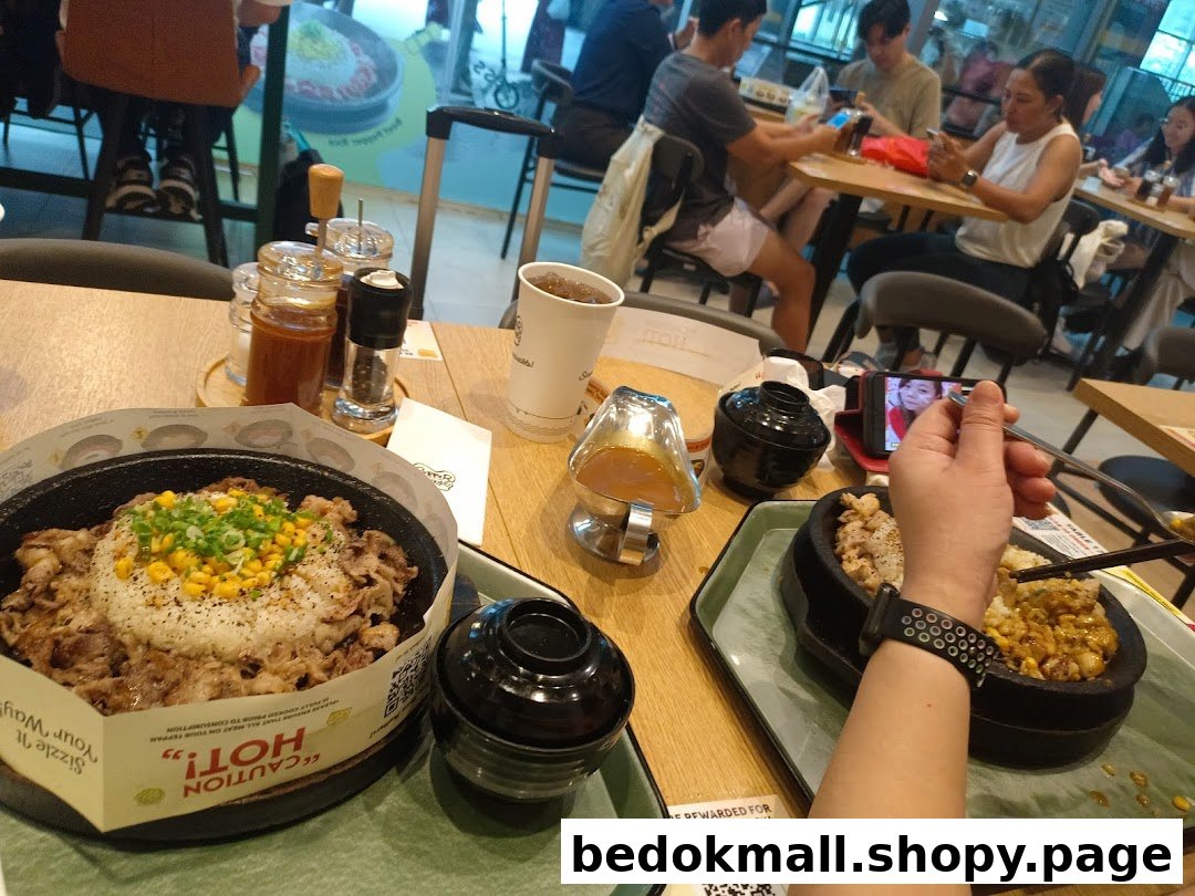 Diners eating hot plate meals at a restaurant table.