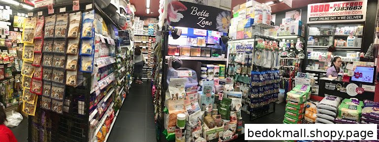 Interior view of a pet supply store with aisles of products and a cashier.