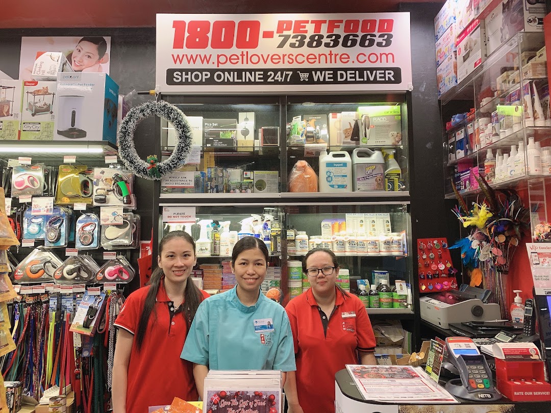 Three staff members stand behind a counter in a pet supply store.
