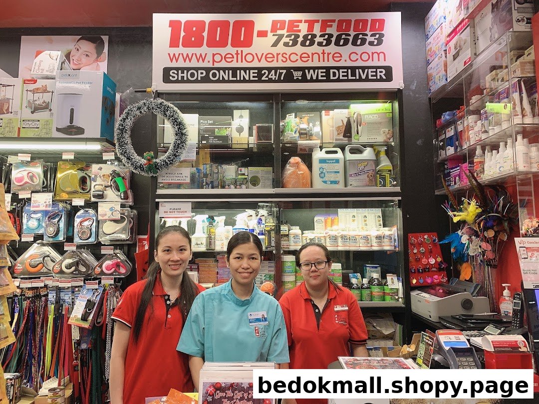 Three staff members stand behind a counter in a pet supply store.
