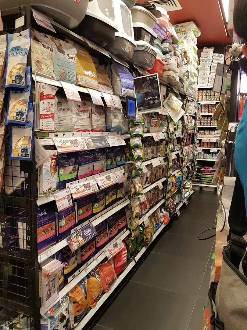 Aisle in a pet store with shelves stocked full of pet food and supplies.