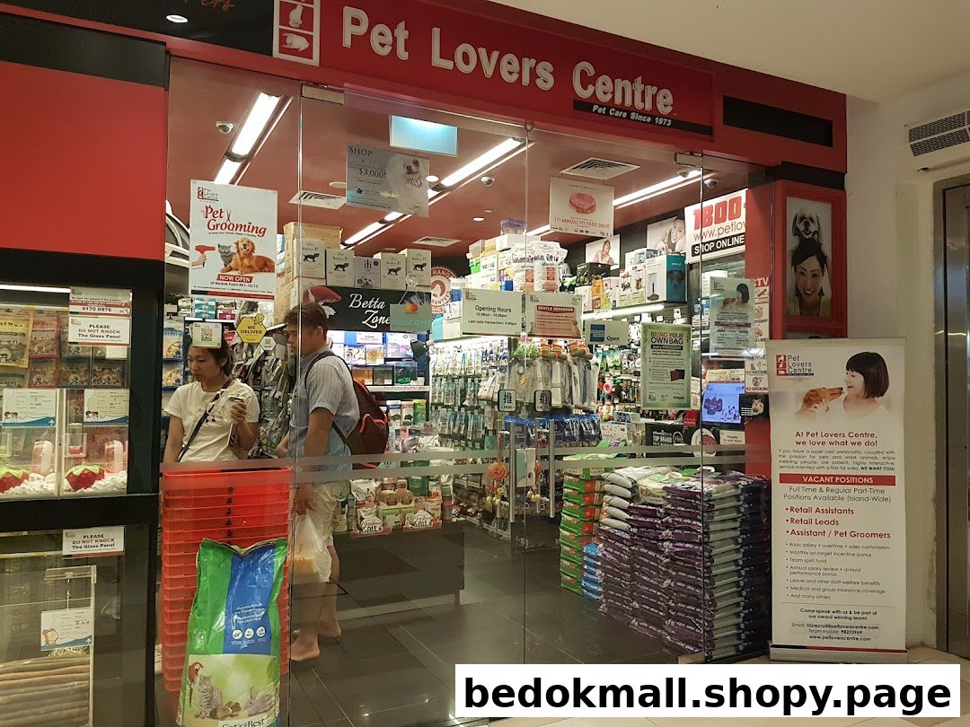 Entrance of a pet shop with glass doors, visible interior, and customers.