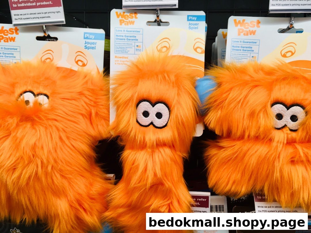 Close-up of several orange furry pet toys displayed on a retail shelf.