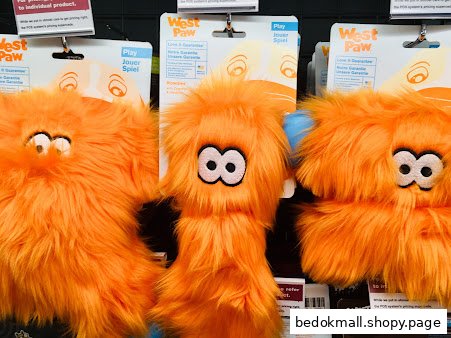 Close-up of orange furry pet toys on display in a shop.