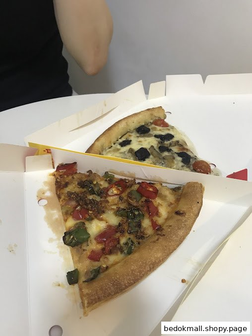 Two pizza slices in takeaway boxes on a white table.