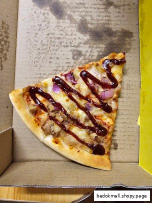 Single slice of pizza with toppings and sauce in a cardboard box.