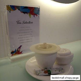 A tea selection menu with a teacup and rolled towel on a counter.