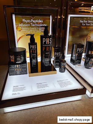 PHS HAIRSCIENCE products displayed on a lighted shelf with prices.