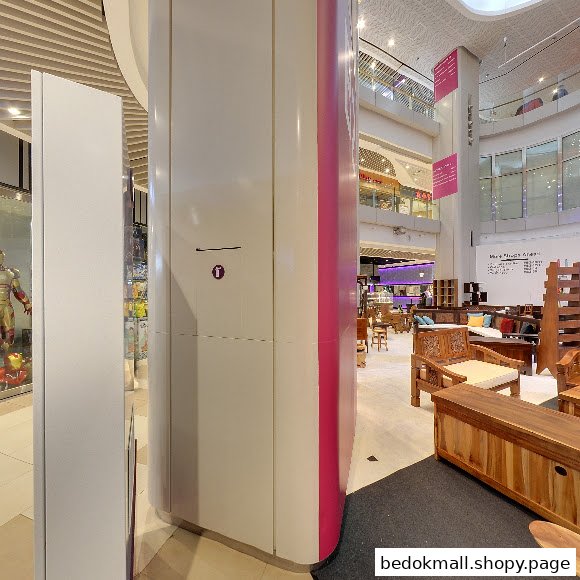 Interior mall view with a pillar, Iron Man display, and furniture shop.