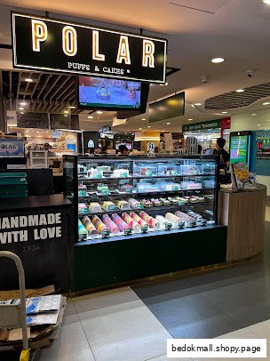 Interior view of a Polar Puffs & Cakes counter with a display case full of pastries.