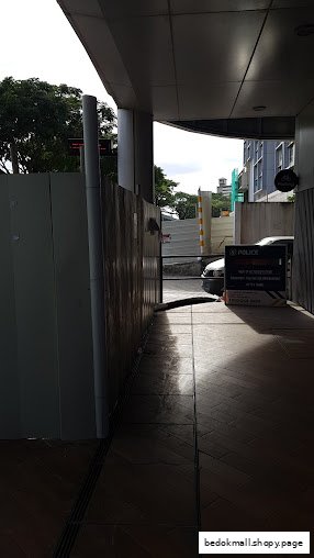 Outdoor view of a building entrance with a construction barrier and car.