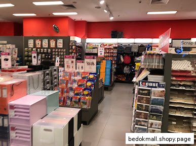 Interior view of a bookstore/stationery shop with aisles of products and red walls.