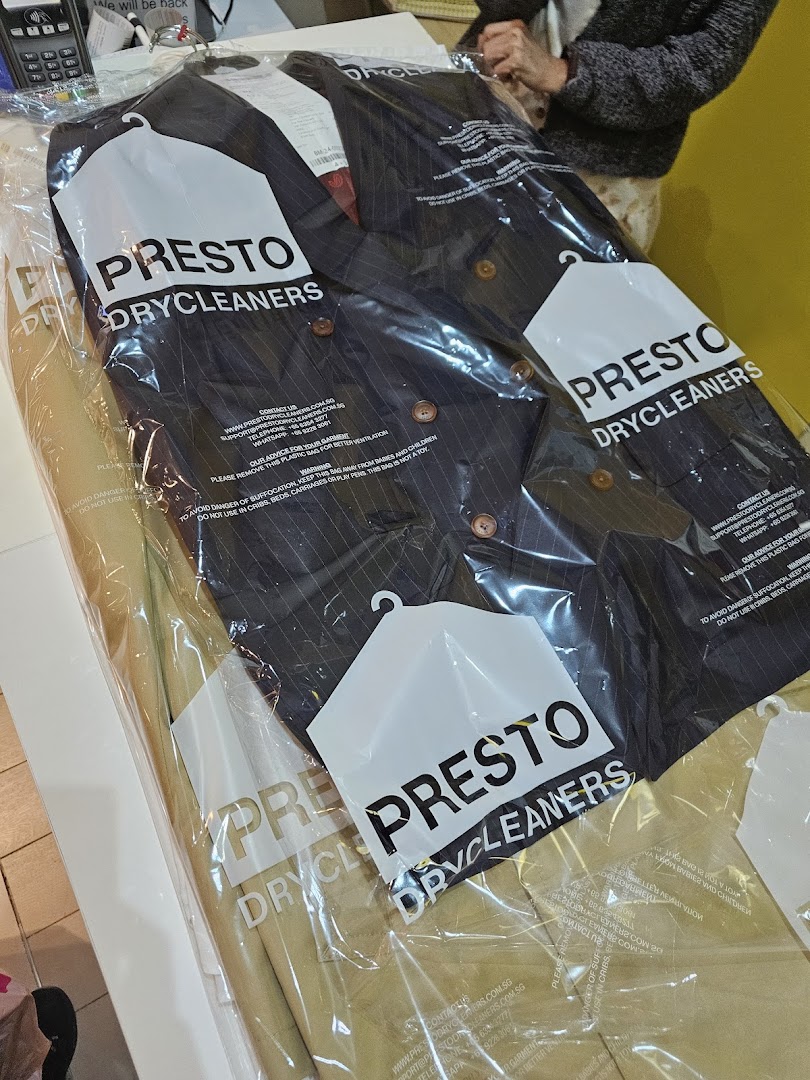 Dry-cleaned clothes in plastic bags on a counter.