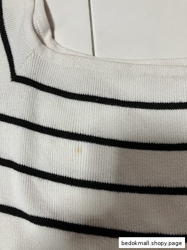 Close-up of a white and black striped garment with a small stain.