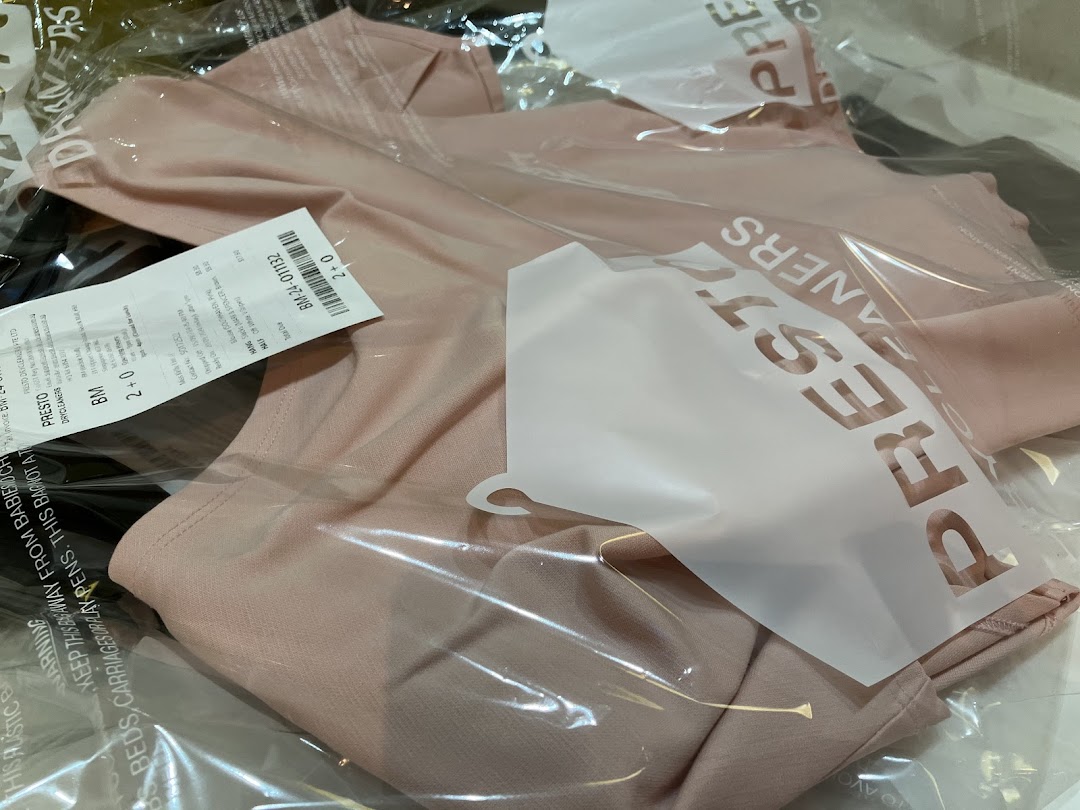 A pink garment in a plastic bag from Presto Drycleaners with a tag.