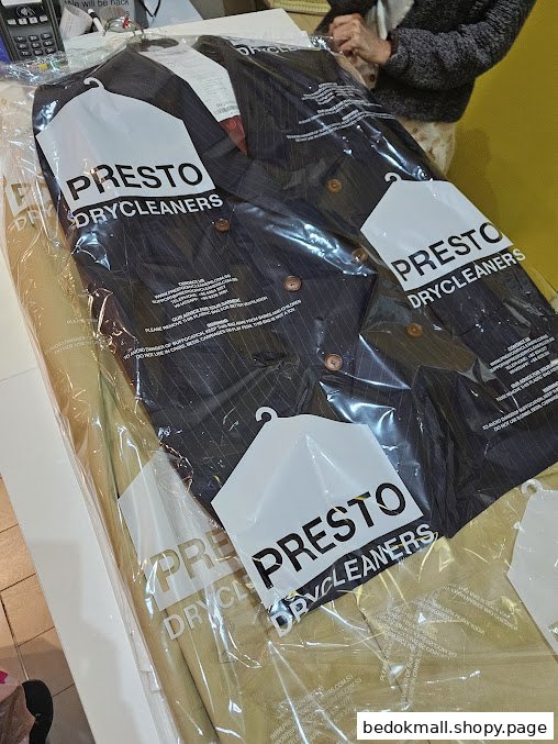 Dry-cleaned clothes in branded plastic bags at Presto Drycleaners.