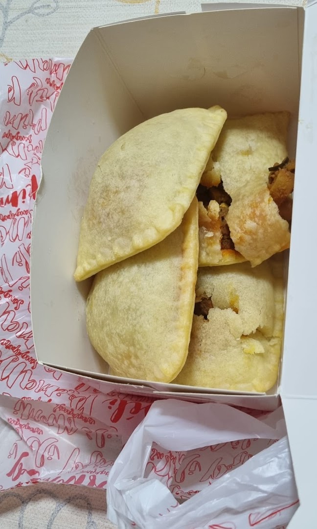 Several pastries in a white box, some broken, with a branded plastic bag.
