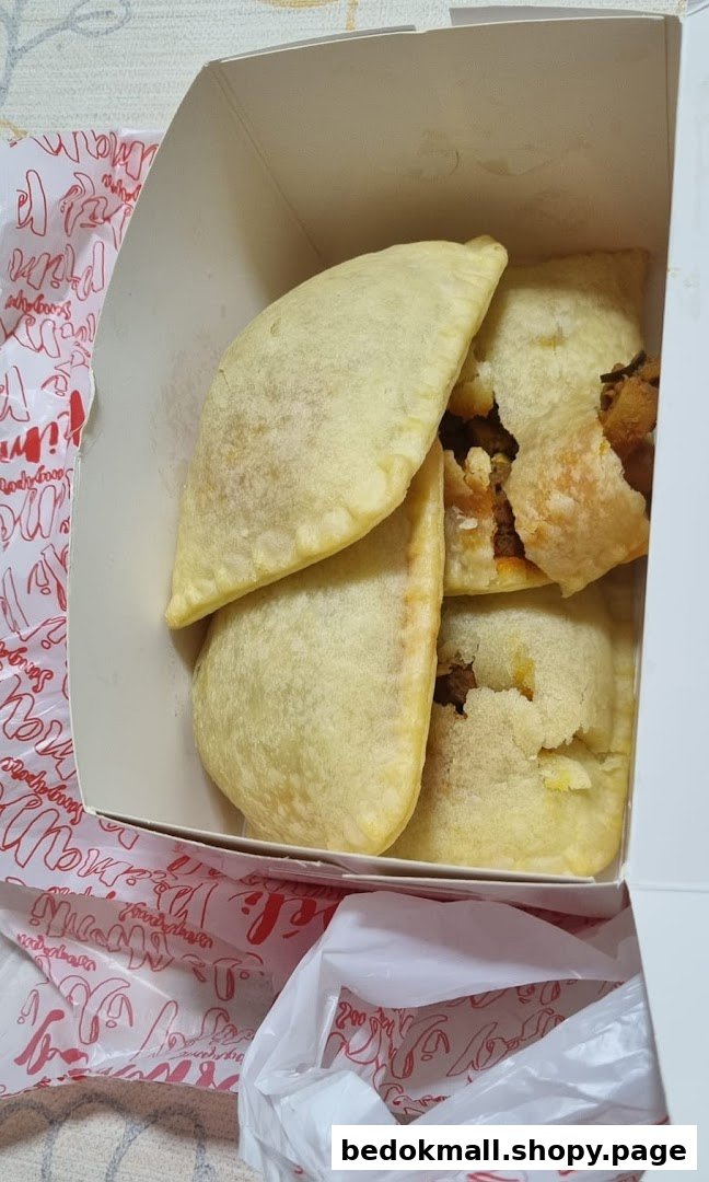 Several pastries in a white box, some broken, with a branded plastic bag.