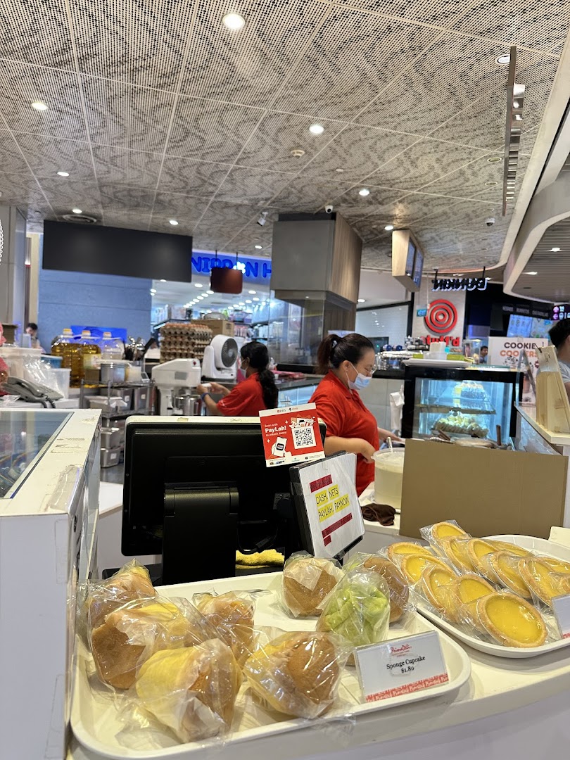 Shop interior with staff, baked goods on display, and a counter.