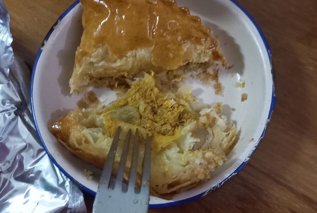 A partially eaten golden pastry with yellow filling in a bowl, with a fork.