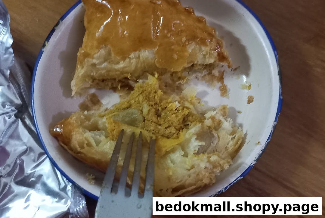 A partially eaten golden pastry with yellow filling in a bowl, with a fork.