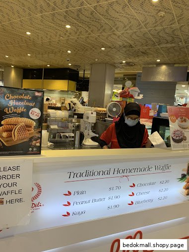 Shop counter with staff and a menu displaying waffle flavors and prices.